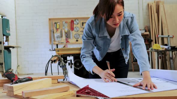 Architect designing her wood construction project on drawing paper in workshop