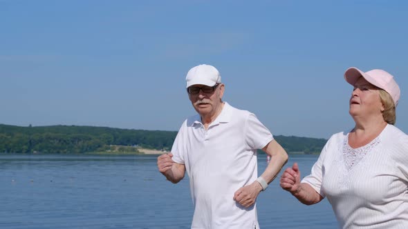 Senior couple running outdoors. In the morning, retirees run to the park near the lake