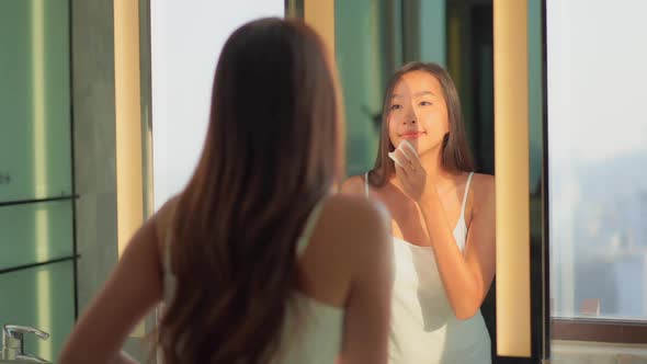 Young asian woman check her face on mirror