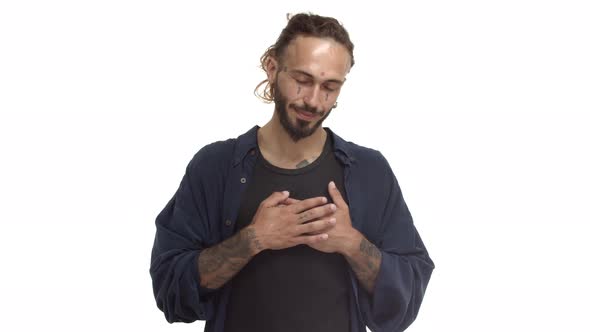 Handsome Bearded Hippie Guy with Tattoos on Body and Face Holding Hands on Heart and Pointing at you