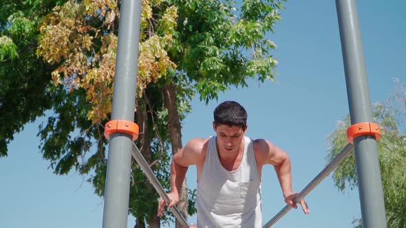 Strong muscular man does a push-up exercise on the push ups bars