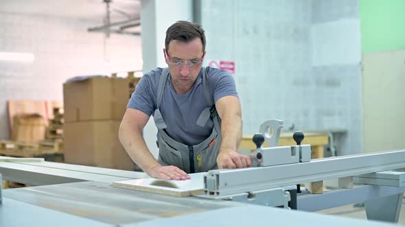 young man works on a circular saw in a furniture workshop