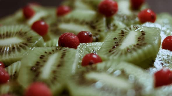 Juicy Fresh Kiwi Slices and Frozen Red Currant Arranged in a Shape of Christmas Tree on a Black