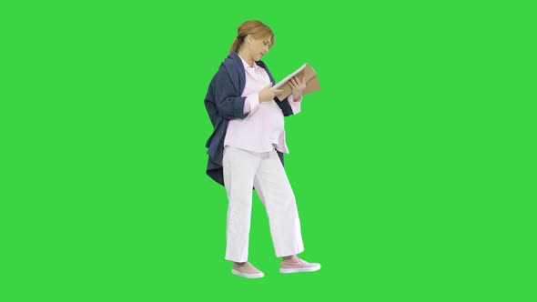 Pregnant Blonde Woman Reading Magazine on a Green Screen, Chroma Key.