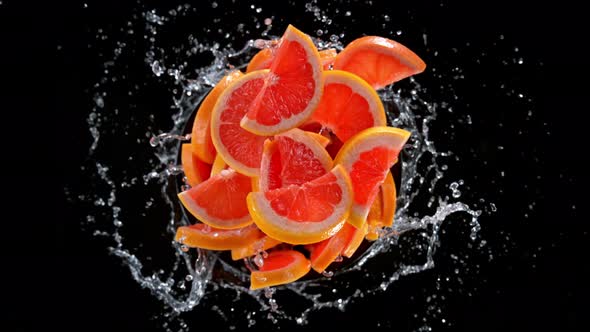Super Slow Motion Shot of Rotating Exploded Grapefruit Slices and Water on Black at 1000Fps