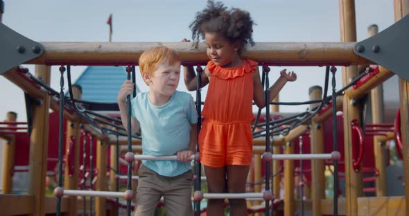 Multiethnic Little Kids Climbing Rope on Outdoors Playground