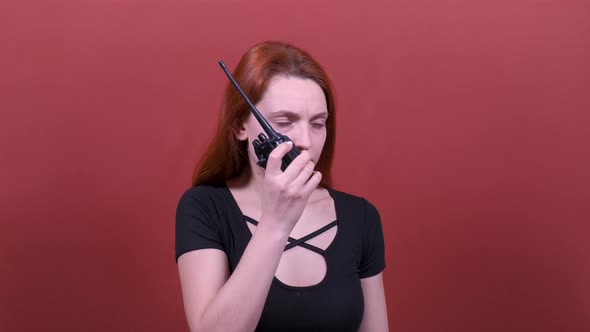 Young Woman with Red Hair Speaks Into a Walkie-talkie.