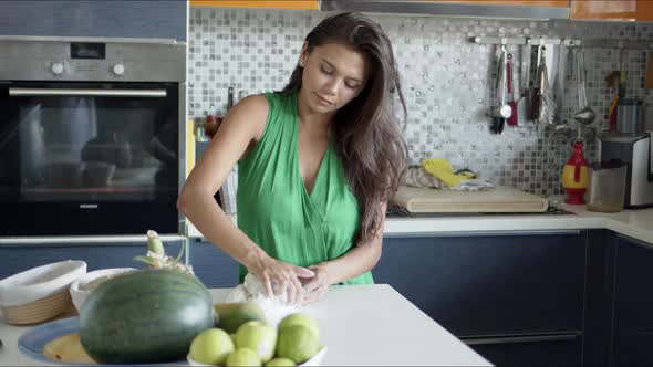 Focused Female Rolling Dough Out While Standing Alone in Light Modern Kitchen