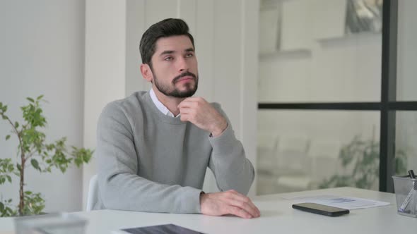 Pensive Young Man Thinking While Sitting in Office