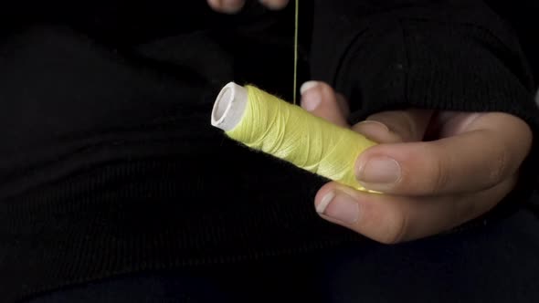 Winding light Yellow sewing thread on spool with both hands