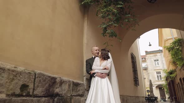 Newlyweds Caucasian Groom with Bride Walking Embracing Hugs in City Wedding Couple in Love