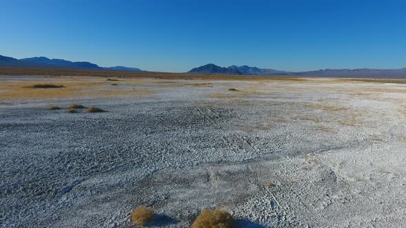 Pan Up From White Sandy Desert with Distant Death Valley Mountains