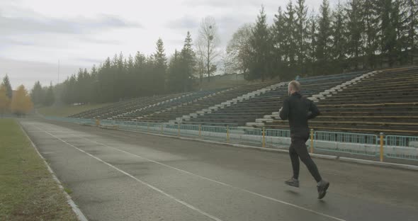 Athlete Is Running Through the Stadium in the Morning in the Foggy Autumn Weather 