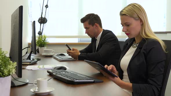 Two Office Workers, Man and Woman, Work on A Tablet and A Smartphone