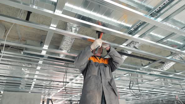 A Construction Worker Assembles Metal Suspended Ceiling Structures