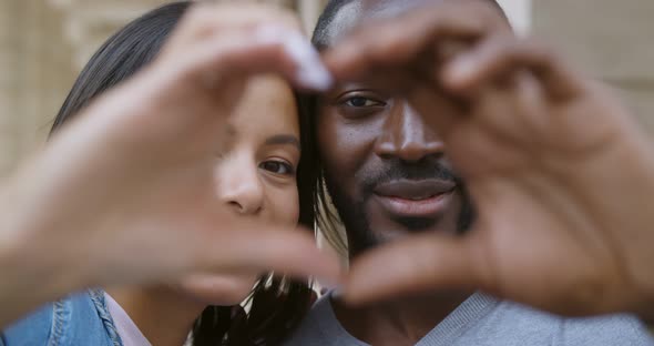 Close Up African Couple Making Heart Shape with Hands Outdoors