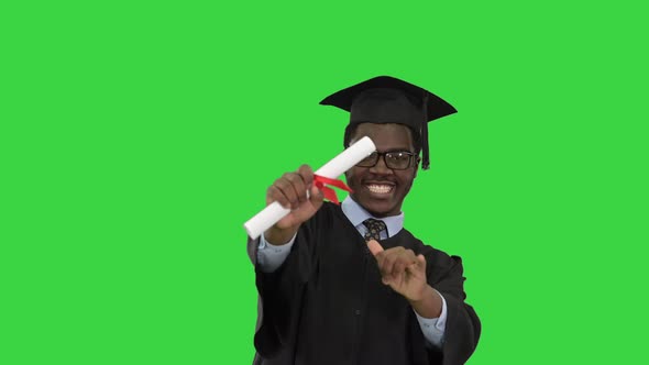 Excited African American Male Student in Graduation Robe Waiving His Diploma and Posing for Camera