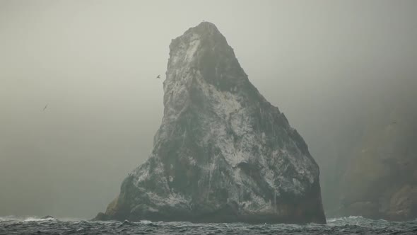 Mist Over the Sea with Rocky Volcanic Cliff is Lit By the Warm Sunset