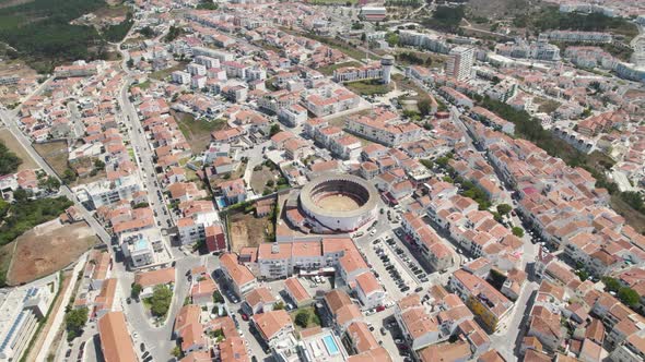 Aerial tilt up over bullring surrounded by residential Houses reveal Nazaré Cityscape