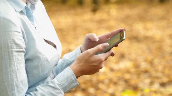 Girl with phone in park. Young woman speaking on mobile phone in park