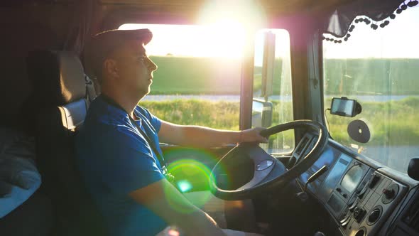 Profile of Lorry Driver Riding Through Countryside at Sunset Time