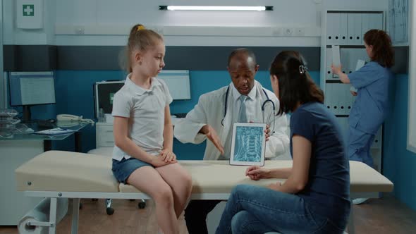 Medic and Parent Checking x Ray Scan Results of Kid to Find Diagnosis