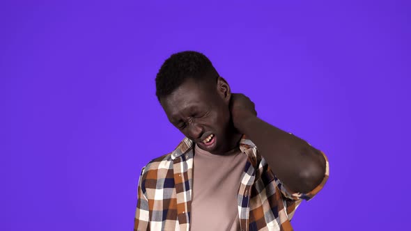 Young African American Man in Plaid Shirt Having Neck Pain or Super Tired Face Grimace