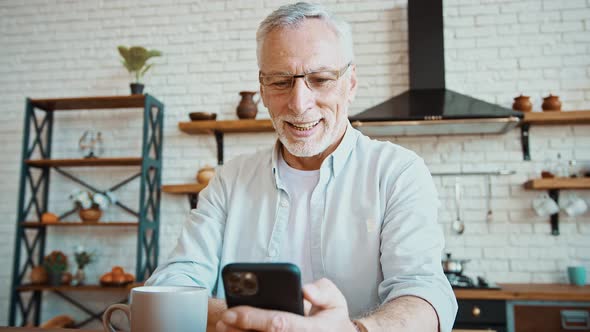 Senior Businessman Drinking Tea Working Online on Cellphone or Having Rest Browsing News Sitting at