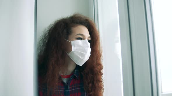 Gorgeous Woman in a Face Mask Is Looking Into the Window