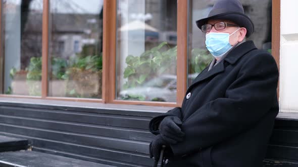 The Pensioner is Sitting on a Bench He is in a Protective Mask Protection From Viruses