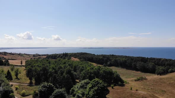 Aerial view of the coastline of Sejerøbugten with hills, fields and ocean.