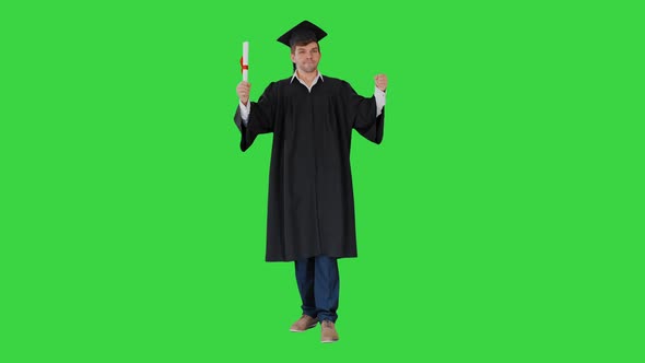 Male Student in Graduation Robe Posing with His Diploma Making Funny Faces on a Green Screen Chroma