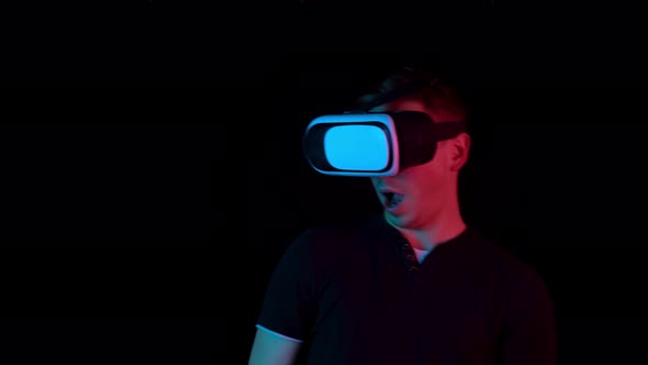 Young Man in VR Glasses. A Man Immersed in Virtual Reality Makes Movements with His Hands. Blue and