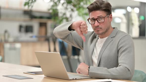 Serious Middle Aged Man with Laptop Showing Thumbs Down