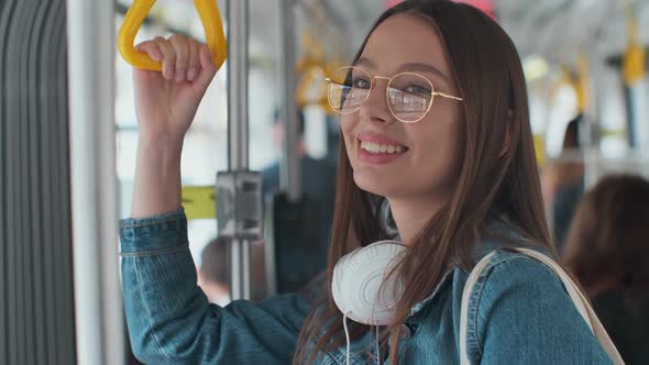 Young Stylish Woman Enjoying Trip in the Modern Tram, Standing with Coffee in the Public Transport