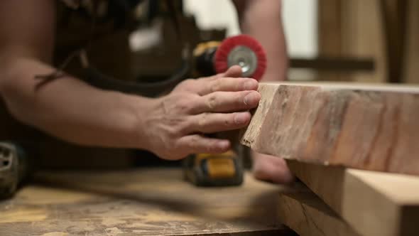 The carpenter blows and shakes off dust from the treated wood surface.