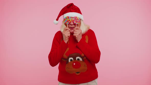 Grandmother in Christmas Sweater Holding Candy Striped Lollipops Hiding Behind Them Fooling Around