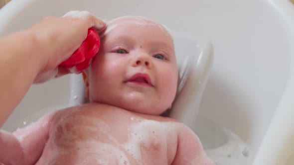 Mother Bathes a Small Child in a Bath