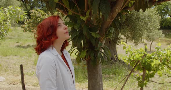 Young agronomist woman with white coat checks the quality of plants in the countryside for crops