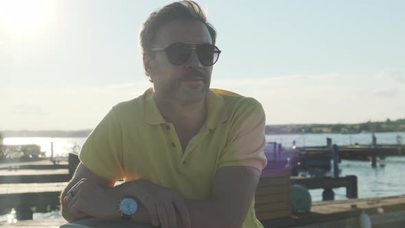 Handsome Good-looking Mature Man Wearing Sunglasses, Yacht Pier in Marina at Background. 