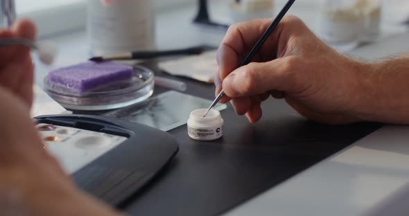 Closeup of Painting a Ceramic Dental Crown with a Thin Brush By Hand