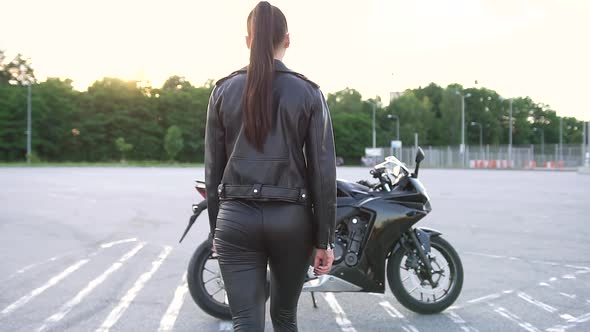 Stylish Brunette which Coming Up to Her Black Cool Motorbike and Getting on