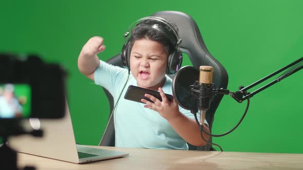 Camera And Asian Little Boy Playing Video Game With Mobile Phone Then Celebrating On Green Screen