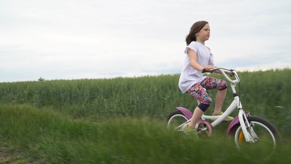 Little girl rides a bicycle on a scenic rural road