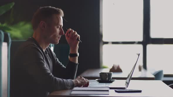 Thoughtful 30s Man Thinking of Problem Solution Working on Laptop