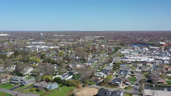 An aerial drone shot over a quiet suburban neighborhood on a sunny day on Long Island, NY.  The came