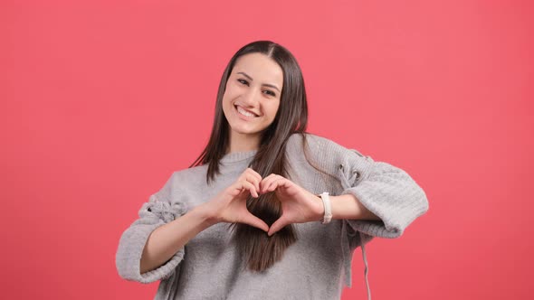 Happy Woman Put Make with Fingers Heart Shape, Isolated Over Red Background.