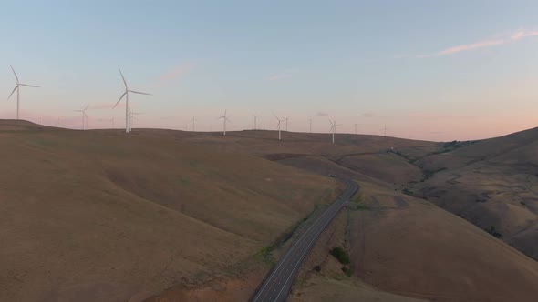 Aerial Landscape View of Wind Turbines on a Windy Hill during a colorful sunrise. Taken in Washingto