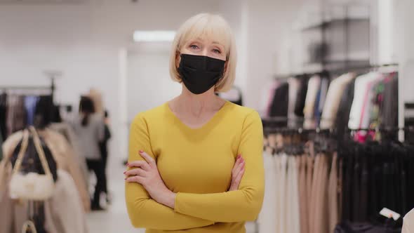 Successful Mature Middle Aged Woman Seller Consultant Clothing Store Owner in Medical Mask Standing