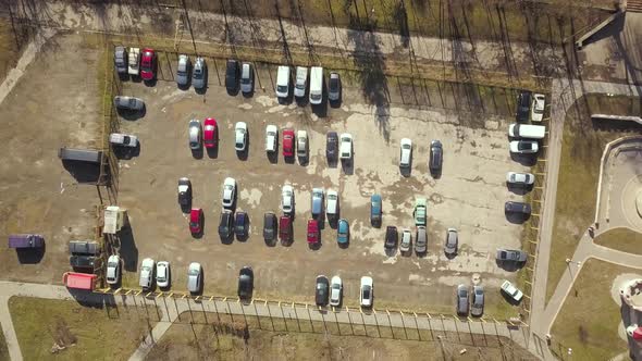 Top down aerial view of old parking lot with ruined dirty surface and many parked cars.